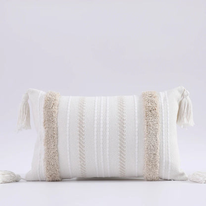 Decorative pillow with textured patterns and tassels on a light gray background