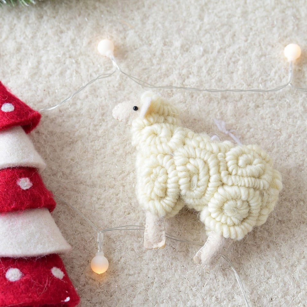 Decorative sheep ornament on a textured surface with fairy lights