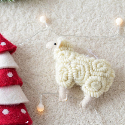 Decorative sheep ornament on a textured surface with fairy lights