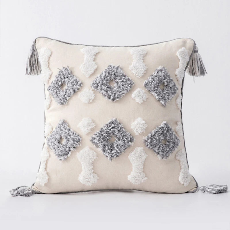 Decorative pillow with geometric patterns and tassels on a light background