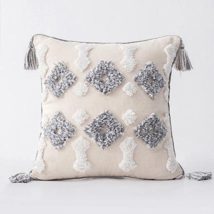 Decorative pillow with geometric patterns and tassels on a light background