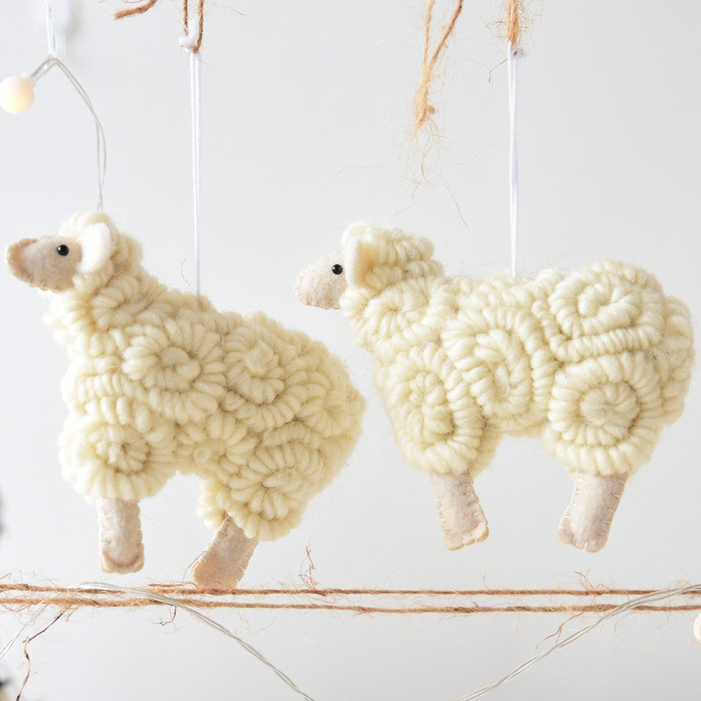 Two white yarn sheep decorations hanging against a light background.