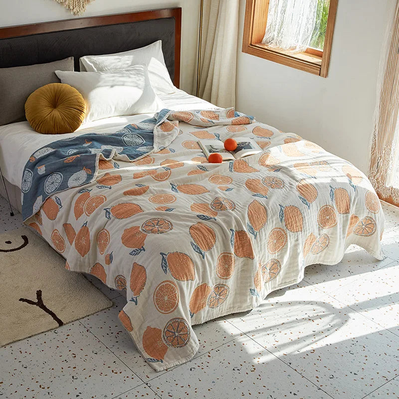 Bed with a decorative blanket featuring orange patterns in a bright bedroom. Bohemian cotton gauze quilted bedspread in 4-layer muslin, breathable summer blanket for bed or sofa, lightweight soft throw in assorted colors and patterns. My Boho Home. .