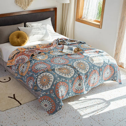 Bed with a patterned quilt in a bright bedroom. Bohemian cotton gauze quilted bedspread in 4-layer muslin, breathable summer blanket for bed or sofa, lightweight soft throw in assorted colors and patterns. My Boho Home. 