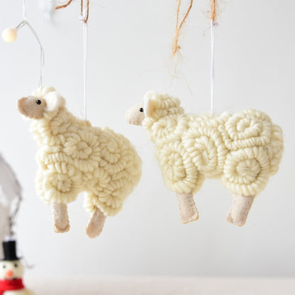 Two white sheep ornaments hanging against a light gray background