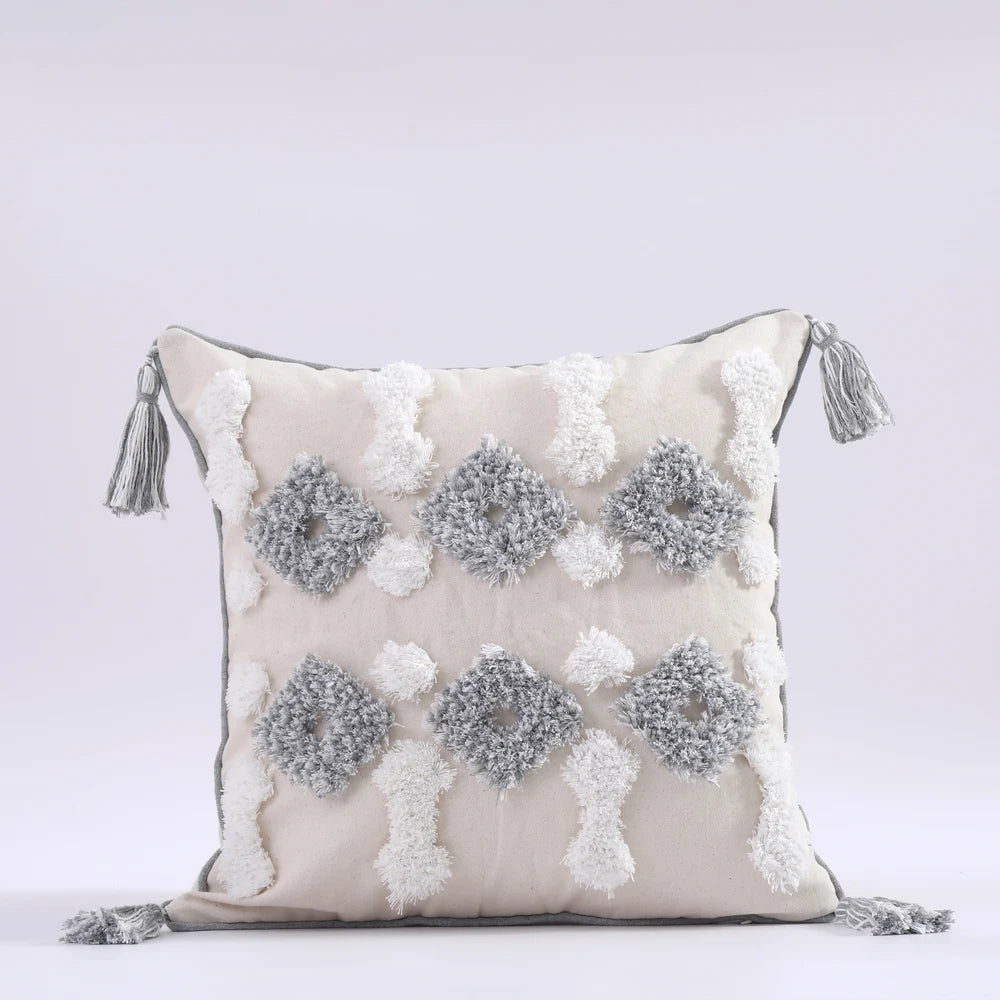 Decorative pillow with pom-pom pattern and tassels on a light gray background