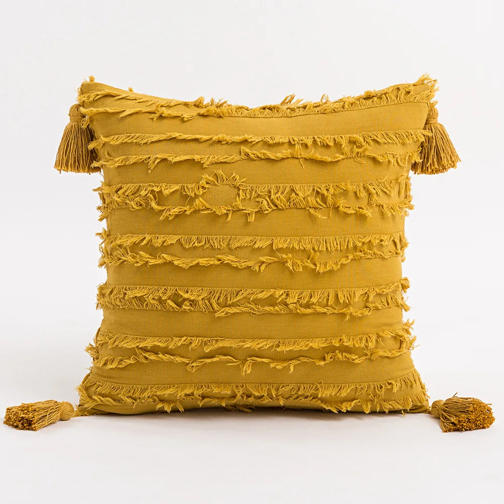 Mustard yellow pillow with tassels on a white background