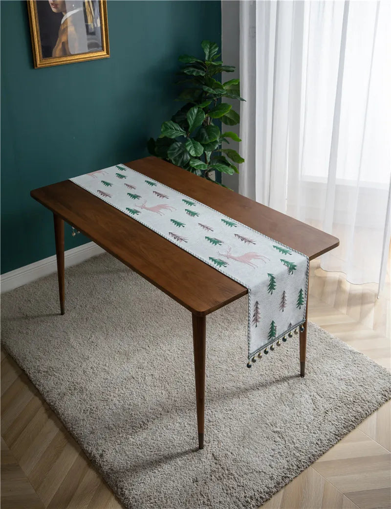 Wooden table with a decorative table runner featuring deer and trees on a gray rug.