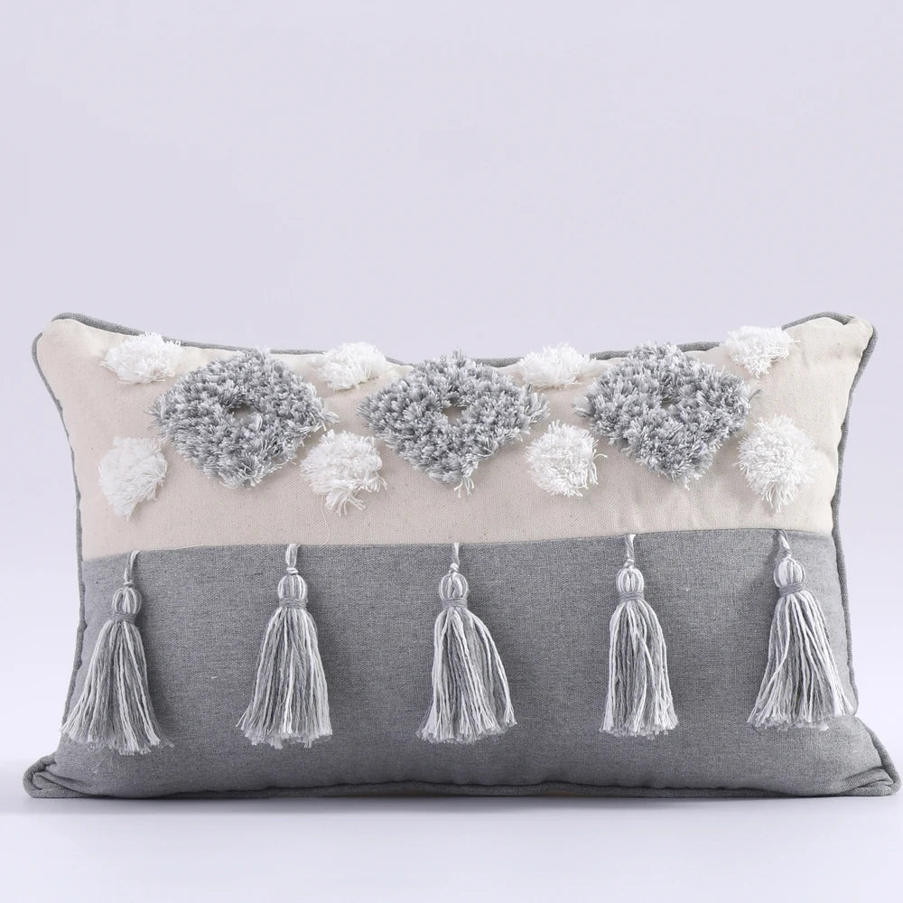 Decorative pillow with tassels and floral embellishments on a light gray background
