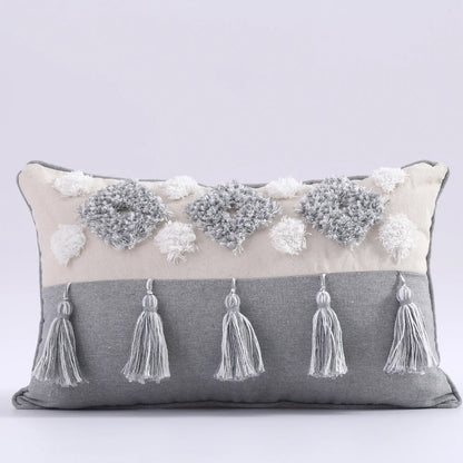 Decorative pillow with tassels and floral embellishments on a light gray background