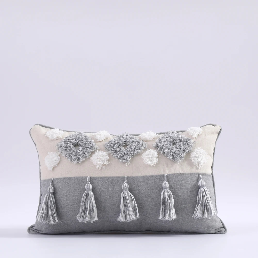 Decorative pillow with tassels and floral embellishments on a light gray background