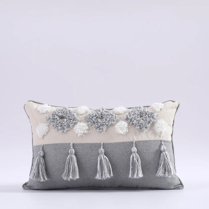 Decorative pillow with tassels and floral embellishments on a light gray background