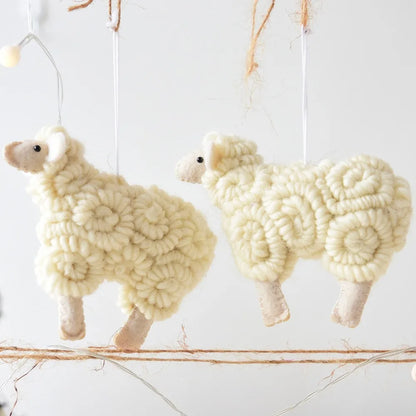 Two white yarn sheep decorations hanging against a light background
