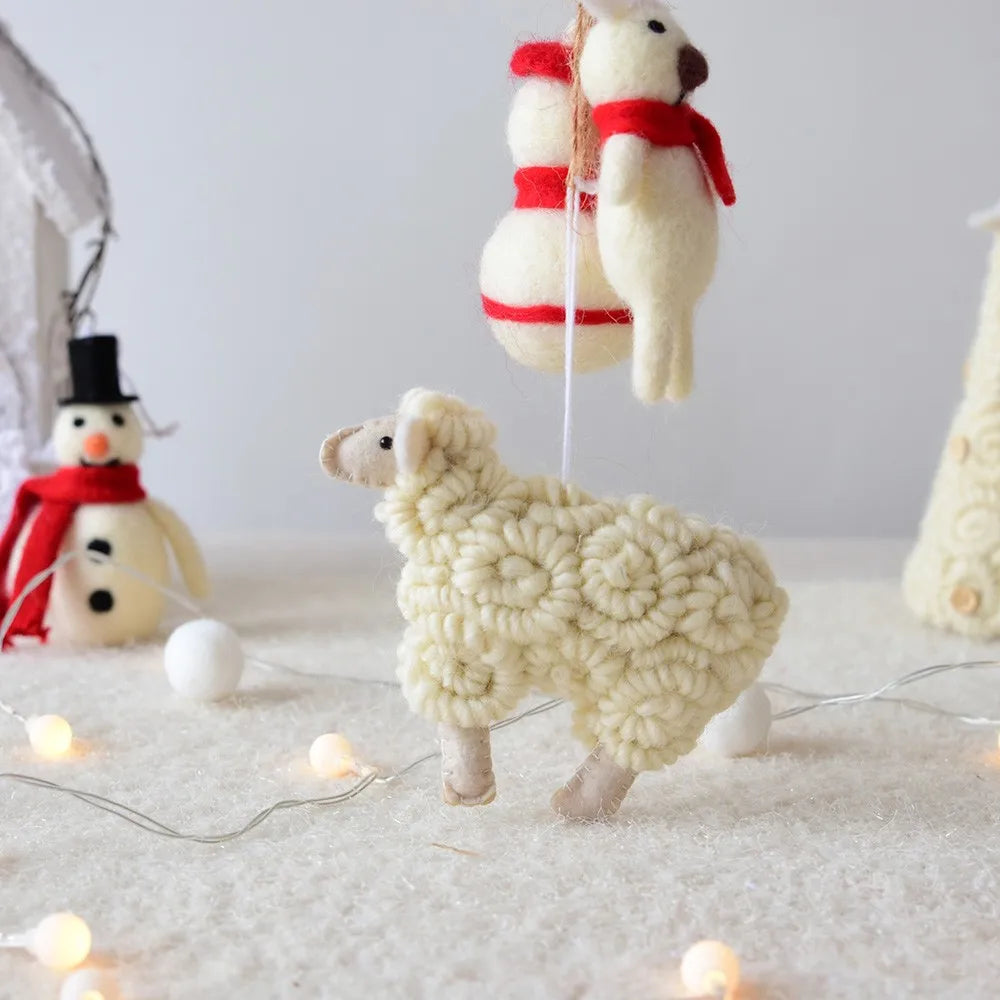 Knitted sheep and snowman toys on a soft surface with string lights.