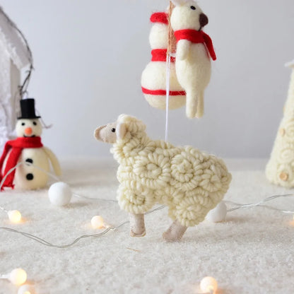 Knitted sheep and snowman toys on a soft surface with string lights.