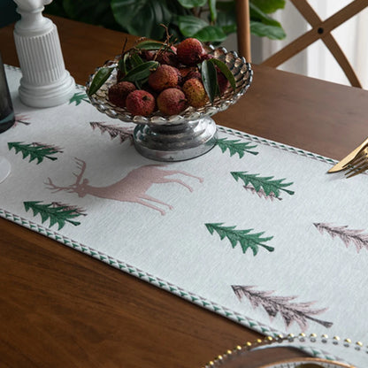 Table runner with deer and tree pattern on a wooden table with a bowl of berries.