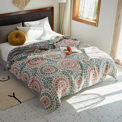Bed with a patterned quilt in a bright bedroom. Bohemian cotton gauze quilted bedspread in 4-layer muslin, breathable summer blanket for bed or sofa, lightweight soft throw in assorted colors and patterns. My Boho Home. 
