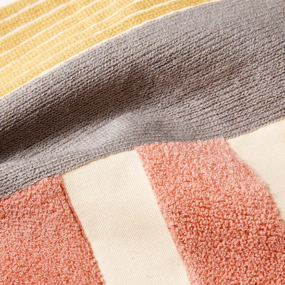 Close-up of a textured fabric with geometric pattern in gray, yellow, pink, and white. Colorful abstract geometric embroidered cushion cover in cotton blend, decorative pillowcase for living room, kids’ room, or boho home decor.