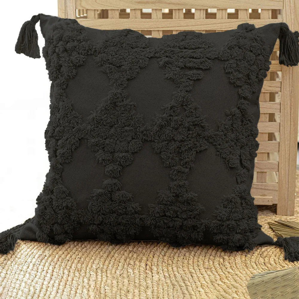 Black textured pillow with tassels on a wooden chair