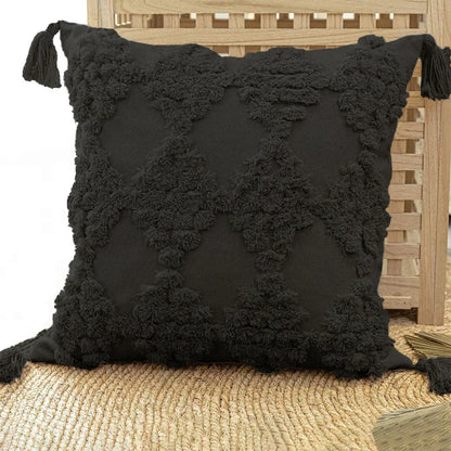 Black textured pillow with tassels on a wooden chair