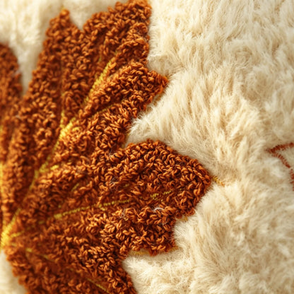 Close-up of a textured knit or crochet fabric with a warm rust-orange leaf motif over a fluffy cream background. Throw pillow from My Boho Home