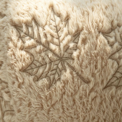 Close-up of a fluffy cream faux fur throw blanket featuring a detailed embroidered leaf pattern.