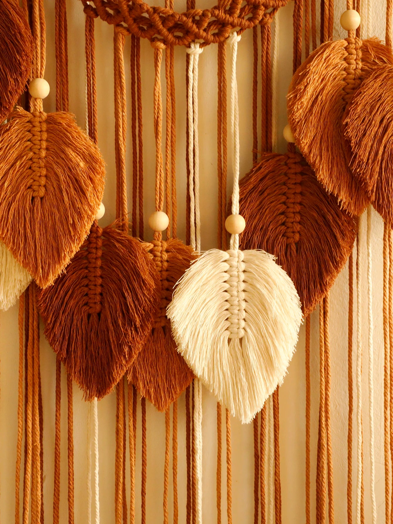 Macrame wall hanging with brown and beige leaves on a striped background