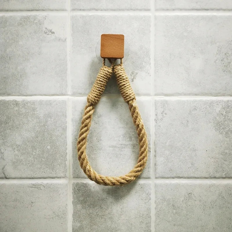 Rope hook with wooden bracket on a tiled wall. Boho rope toilet paper holder, nail-free wall mounted paper towel rack, rustic bathroom storage and decor accessory with wood and rope design