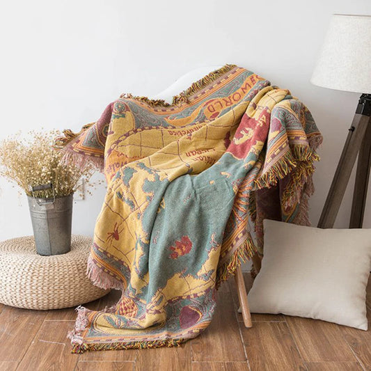 Colorful patterned blanket draped over a chair in a room with a lamp and plant. Bohemian world map woven blanket cotton sofa throw home decor