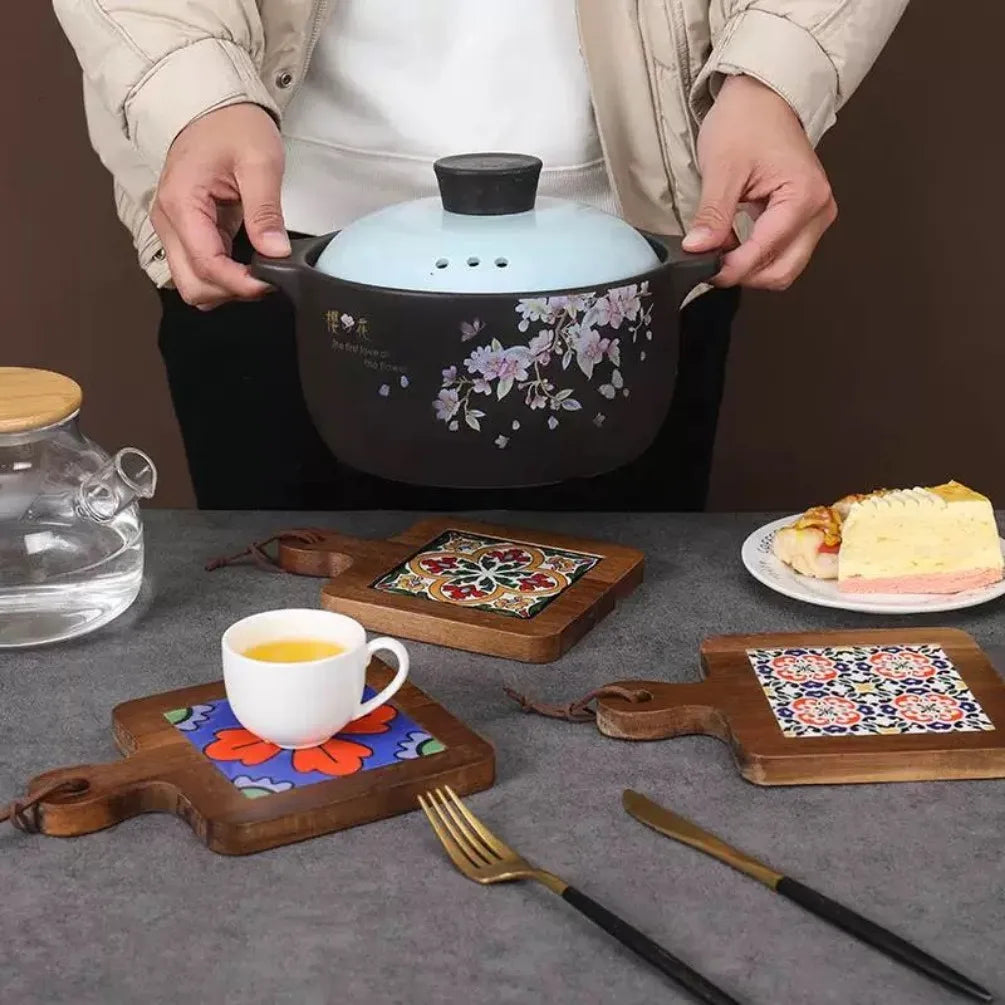 Person holding a floral-patterned pot on a table with a cup, teapot, and food.