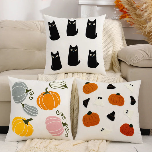 Decorative pillows with black cats and pumpkins on a couch.