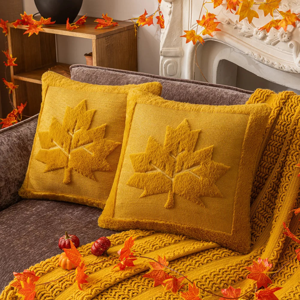 Yellow pillows with leaf patterns on a couch, surrounded by autumn decorations. Halloween pumpkin plush pillow cover for sofa and bed decor.