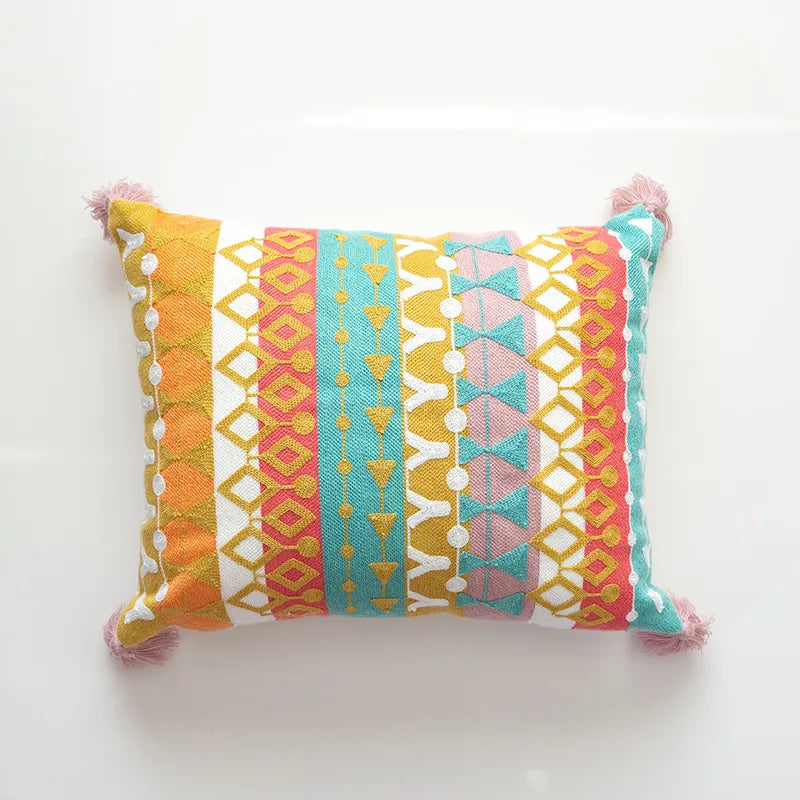 Colorful patterned pillow with pom-pom accents on a white background