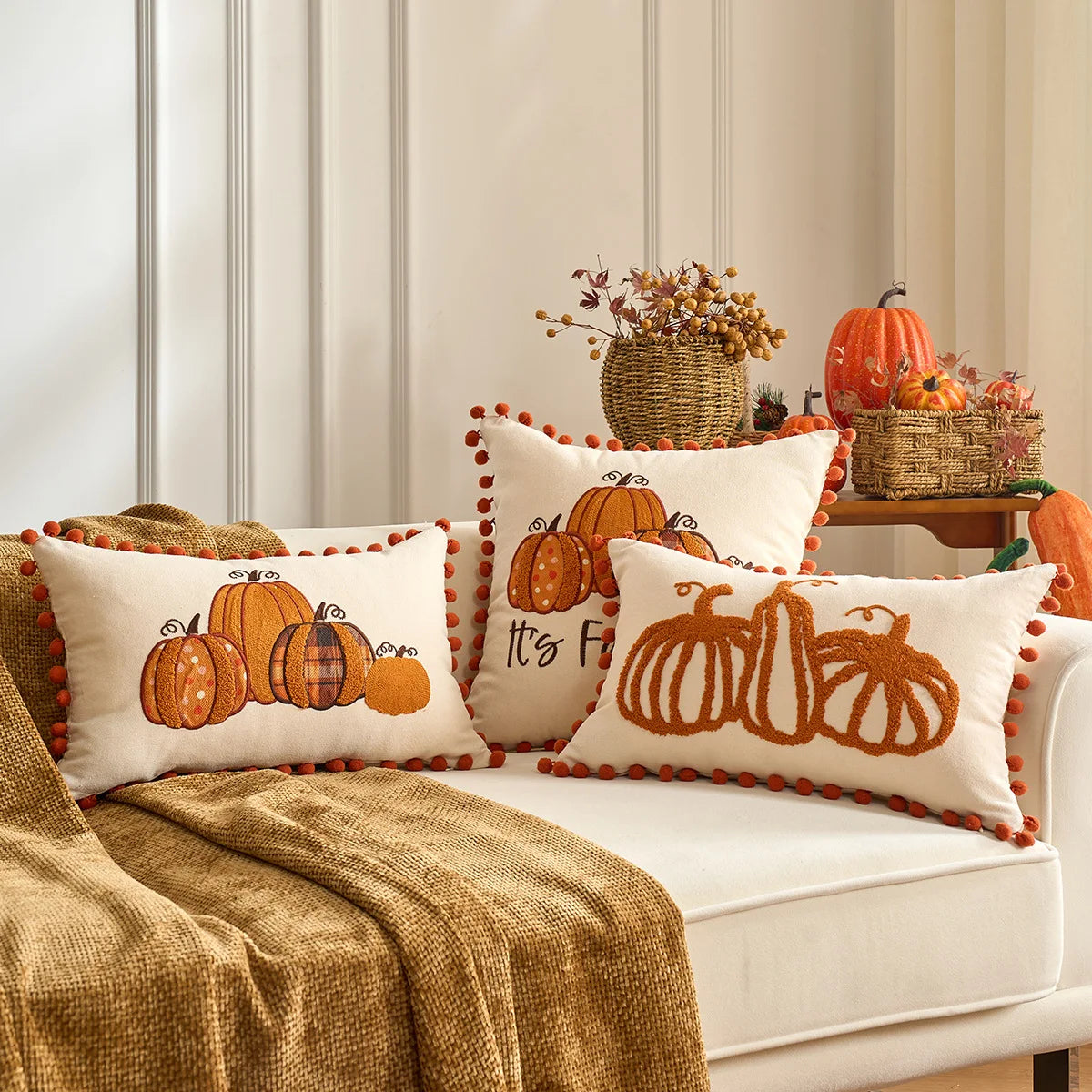 Decorative pillows with pumpkin designs on a sofa in a cozy living room. Fall maple leaf and pumpkin throw pillow cover for Thanksgiving decor