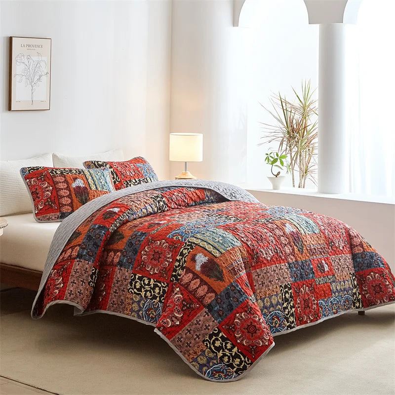 Colorful patchwork quilt on a bed in a bright bedroom with a lamp and plant. Lightweight boho quilted bedspread set with pillow shams, soft all-season coverlet for queen, king, full, or twin beds in modern cloud pattern design.