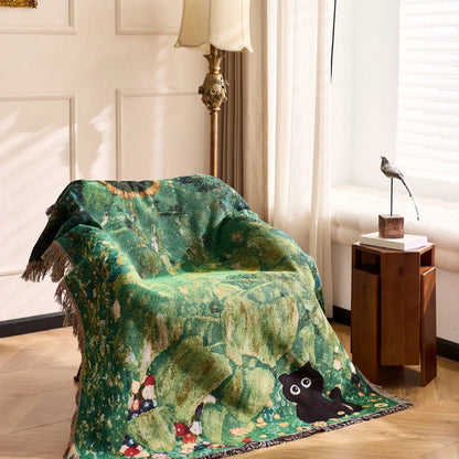 Green patterned blanket draped over a chair in a room with a lamp and small table. Cat woven throw blanket for boho sofa and home decor