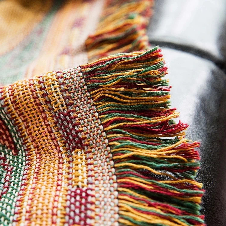 Close-up of a woven fabric with colorful fringes on a blurred background Travel-inspired cotton plaid bed cover and decorative boho blanket