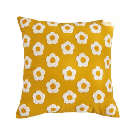 Yellow pillow with white floral patterns on a white background