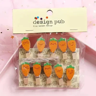 Packaged carrot-shaped clips with cute faces on a pink background, branded 'design pub'.