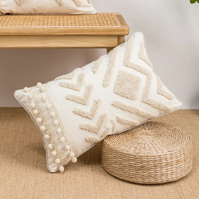 Decorative pillow with geometric pattern and pom-pom trim on a woven surface. Nordic blue tufted cushion cover with geometric stripe and grid crochet pattern, tassel pillow cover for sofa, bed, and boho home decor