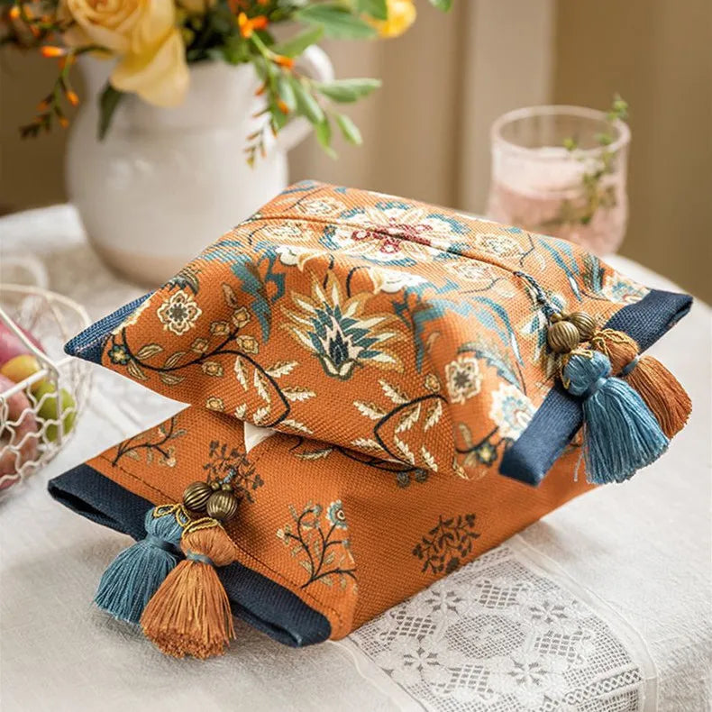 Decorative pillows with floral patterns and tassels on a table with a lace tablecloth. boho home decor, reusable tissue bag, cotton tassel tissue holder, plush tissue organizer, bathroom tissue box cover, car tissue case, American style tissue pouch, soft fabric tissue holder, decorative tissue box, housewarming gift, eco-friendly storage