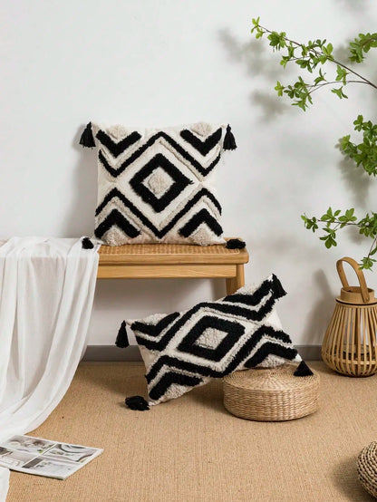 Black and white patterned pillows on a wooden chair and woven stool with a plant in the background. Nordic Moroccan tufted throw pillow cover in geometric jacquard design, boho accent cushion for sofa, bed, or car, available in 12x20 inch lumbar and 18x18 inch square sizes – cozy textured boho home decor.