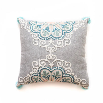 Decorative pillow with intricate lace-like embroidery on a light gray background