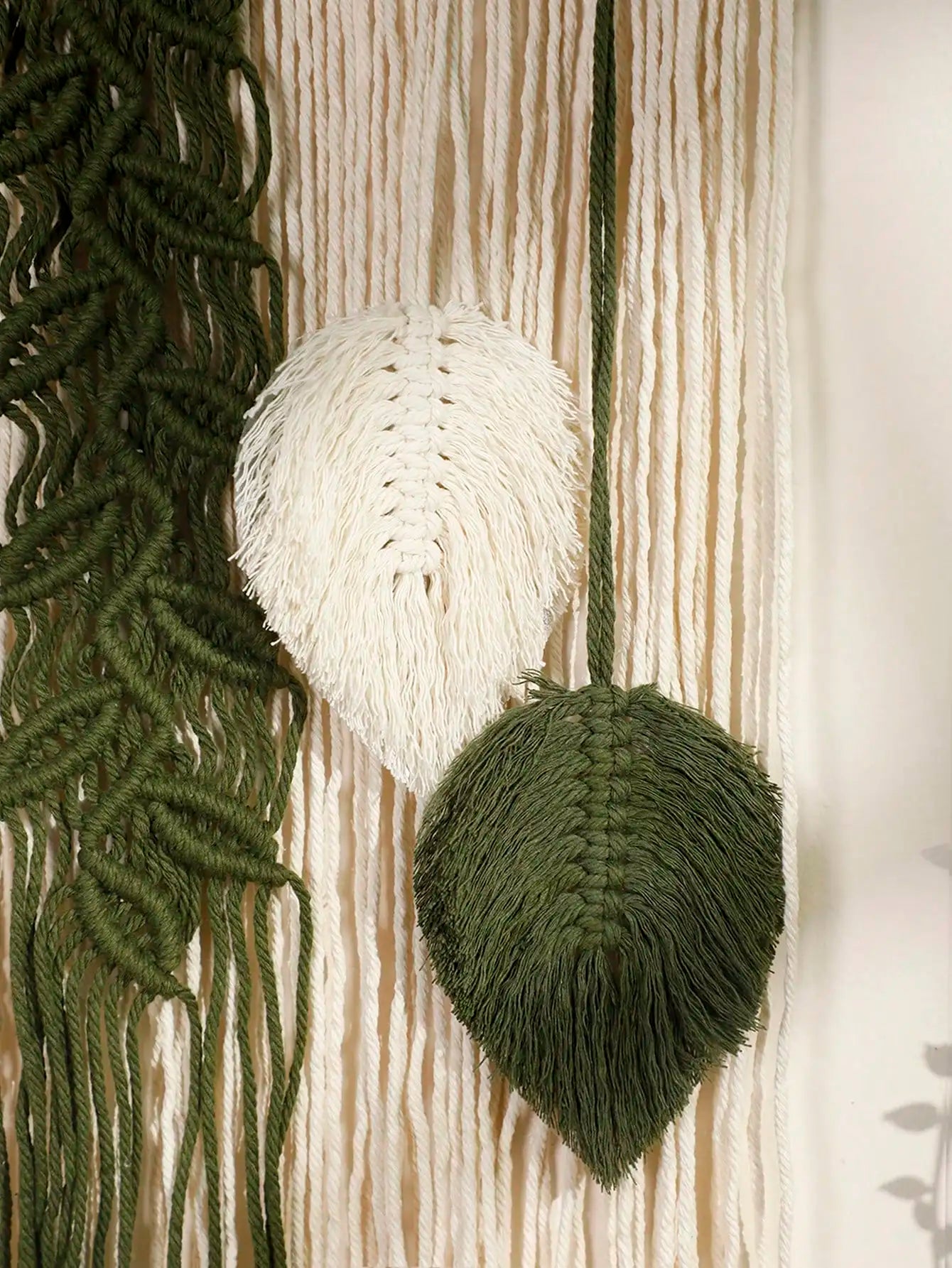 Decorative wall hanging with woven leaf shapes in green and white.