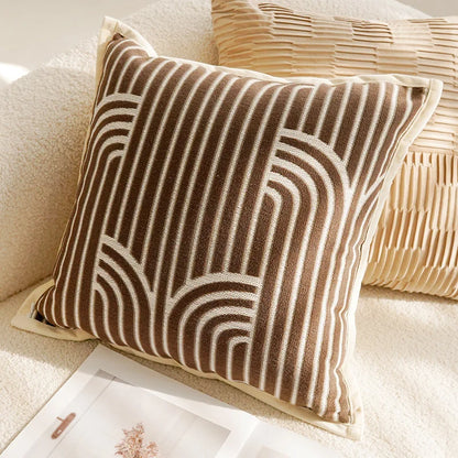 Decorative pillow with brown and beige abstract pattern on a light-colored sofa.