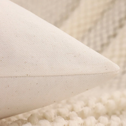 Close-up of a textured beige pillow on a soft surface. Christmas embroidered pillow cover with tufted snowflake and reindeer design in 18x18 inches, festive canvas cushion case for sofa or bed