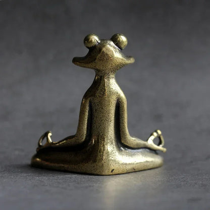 Bronze frog sculpture in a meditative pose on a dark background
