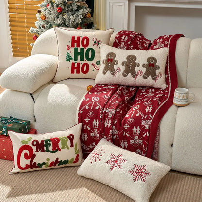 Decorative Christmas pillows with Ho Ho Ho, Gingerbread Men, Merry Christmas and snowflakes and blanket on a sofa with festive decor.