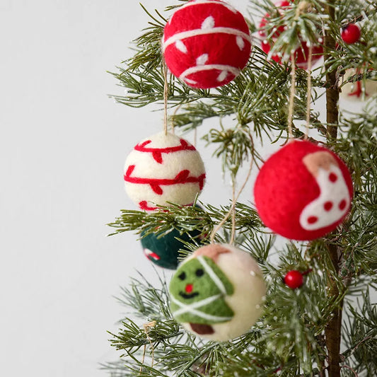 Decorative wool felt Christmas ornaments on a tree with a plain background