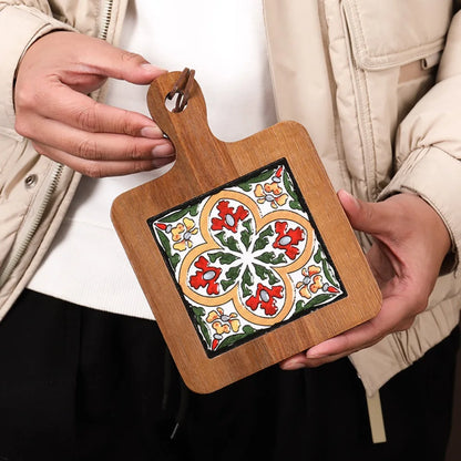 Small wooden trivet with a decorative tile design held by hands.